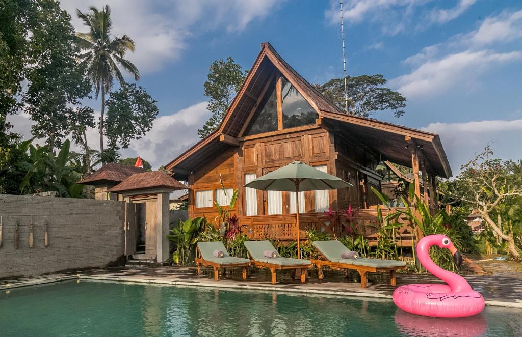 a house with a swimming pool and a pink flamingo at Benisari Batik Garden Cottage in Ubud