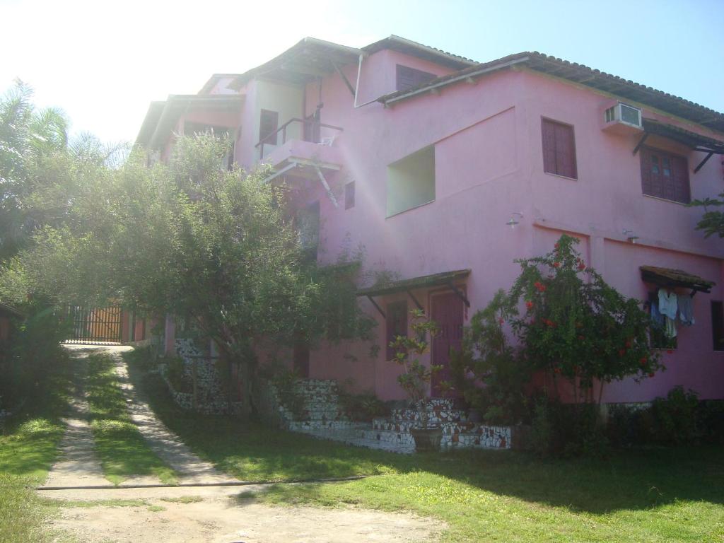 uma casa cor-de-rosa com árvores à frente. em Residencial Ravasco em Camamu