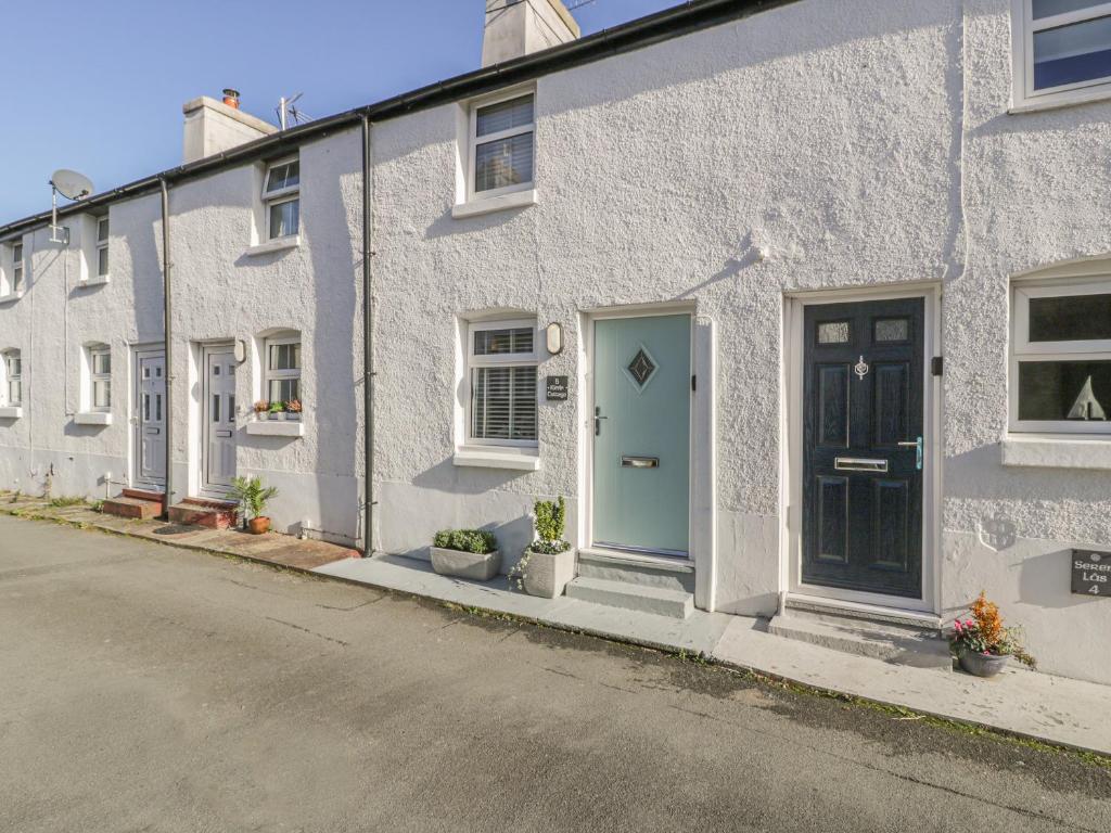 a white building with a blue door on a street at Kirrin Cottage in Conwy