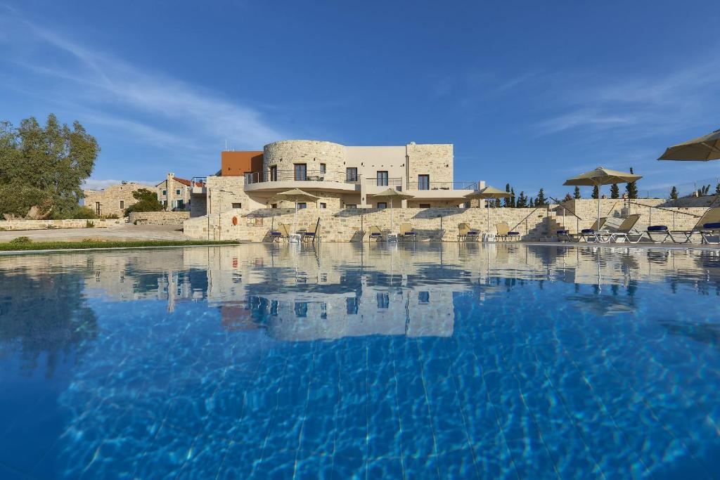 une grande piscine d'eau en face d'un bâtiment dans l'établissement Orelia Cretan Deluxe Apartments, à Kamilárion