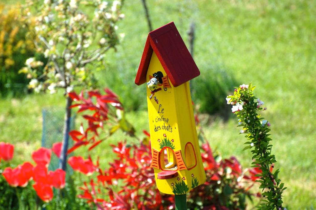 ein gelbes Vogelhaus in einem Garten mit Blumen in der Unterkunft Relais de La Brande in Saint-Gourson