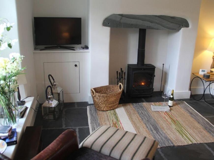 a living room with a fireplace with a couch and a television at Beck Steps 1 in Grasmere