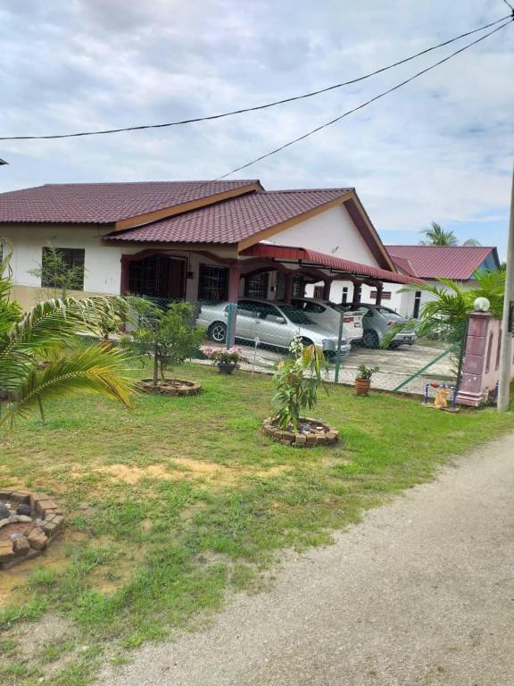 una casa con coches aparcados delante de ella en AMIMAS HOMESTAY en Kampong Telok