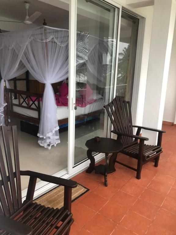 two chairs and a table in a room with a bed at La Veranda Di Serena in Unawatuna