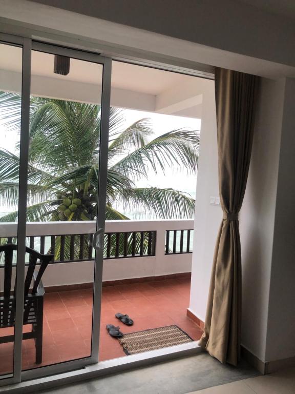 an open door to a balcony with a palm tree at La Veranda Di Serena in Unawatuna