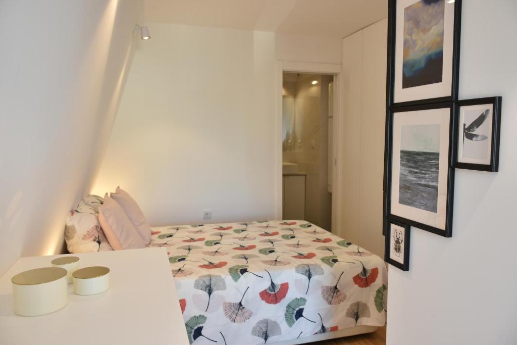 um quarto com uma cama, uma mesa e fotografias em Sunny Penthouse whith balcony 9min walk main station em Porto