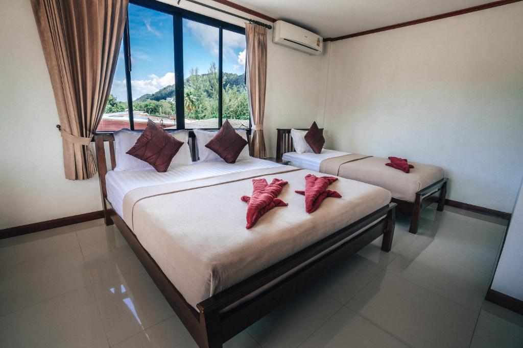 two beds in a room with a window at Phra Ae Apartments in Ko Lanta