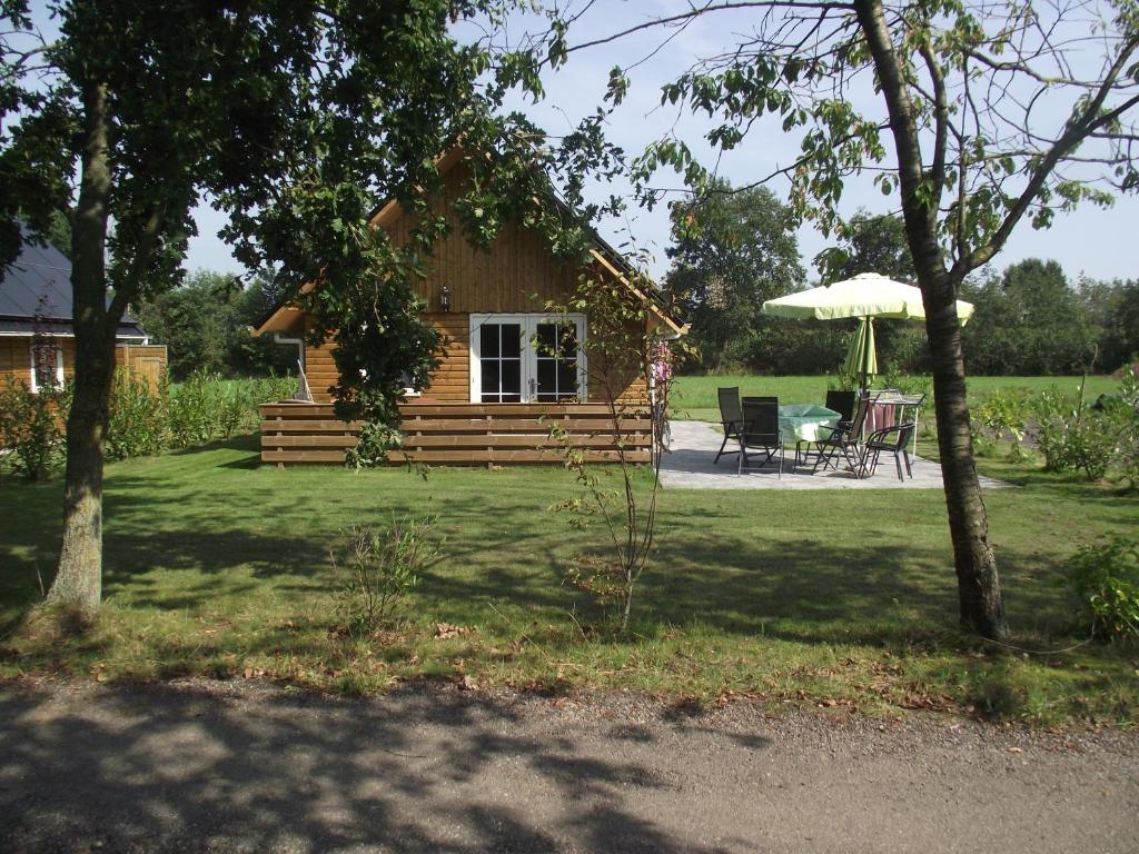 a log cabin with a table and an umbrella at Vakantiehuisjes Landgoed Sonneborghe in Kollumerzwaag