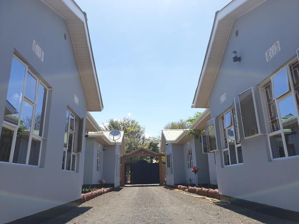 an alley between two white houses with a driveway at Le Parlour in Boma la Ngombe