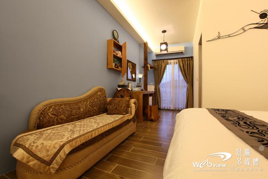 sypialnia z łóżkiem i kanapą w pokoju w obiekcie 緣木屋庭園民宿 w mieście Dongshan