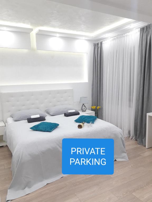 a bedroom with a white bed with the words private parking at Abbazia Apartments Free Parking Near Center and Vrbas River in Banja Luka