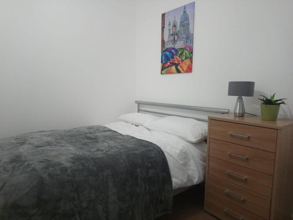 a bedroom with a bed and a dresser with a lamp at 1 Bedroom Flat in Sheffield City Centre-Sleeps 4 in Sheffield