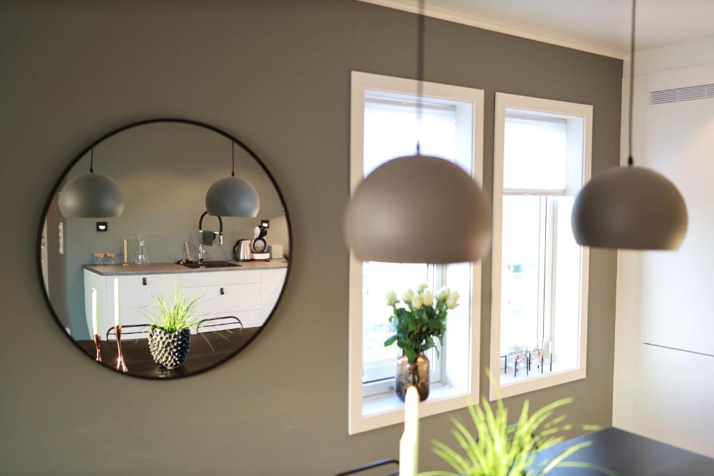 een spiegel in een kamer met een tafel en twee ramen bij Modern apartment with seaview in Hamarvik