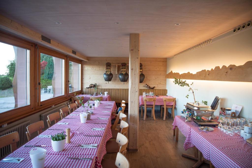 une salle avec tables et chaises et nappes roses dans l'établissement Restaurant und Kaeserei Berghof, à Ganterschwil