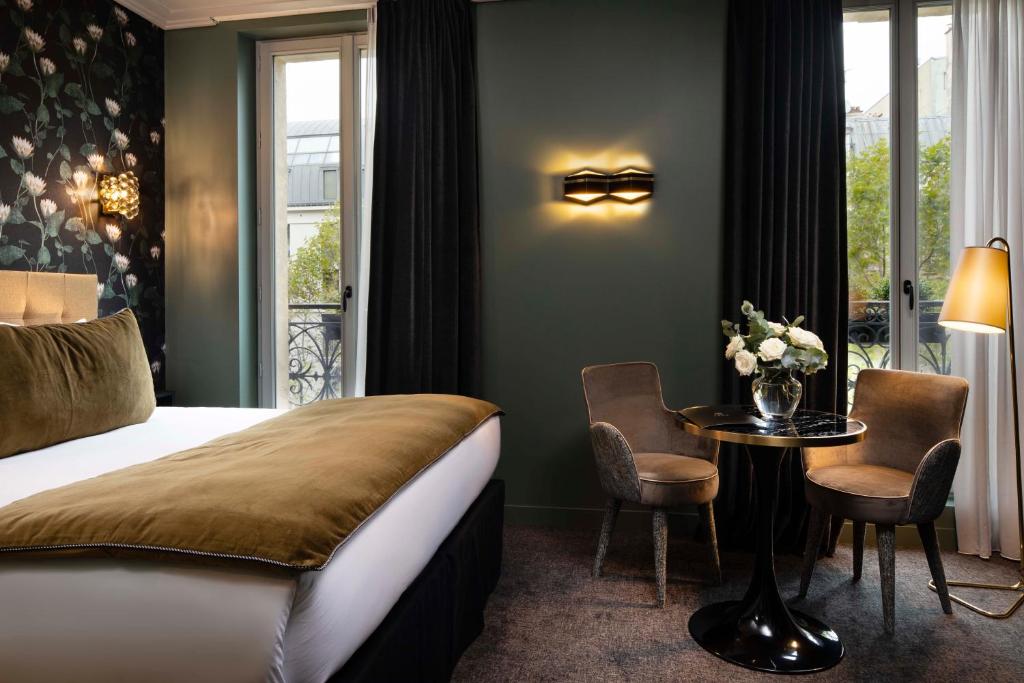 um quarto de hotel com uma cama e uma mesa com cadeiras em Rayz Eiffel em Paris