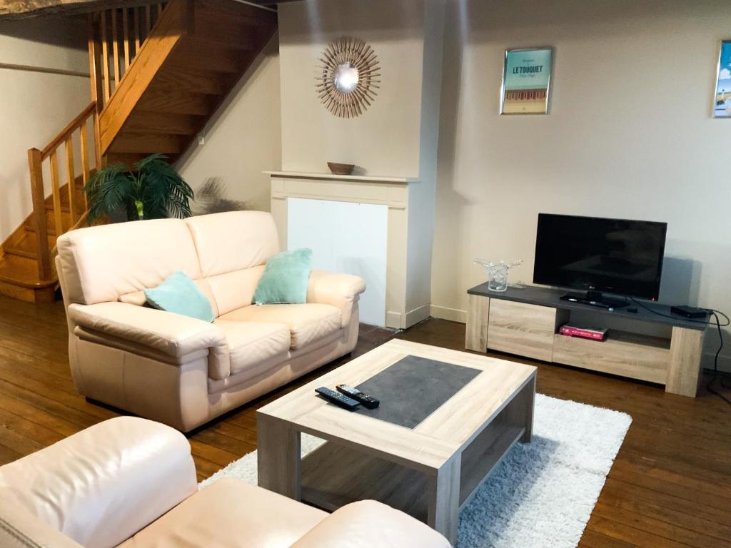 Grand appartement idéalement situé 7 places في Desvres: غرفة معيشة مع أريكة بيضاء وتلفزيون