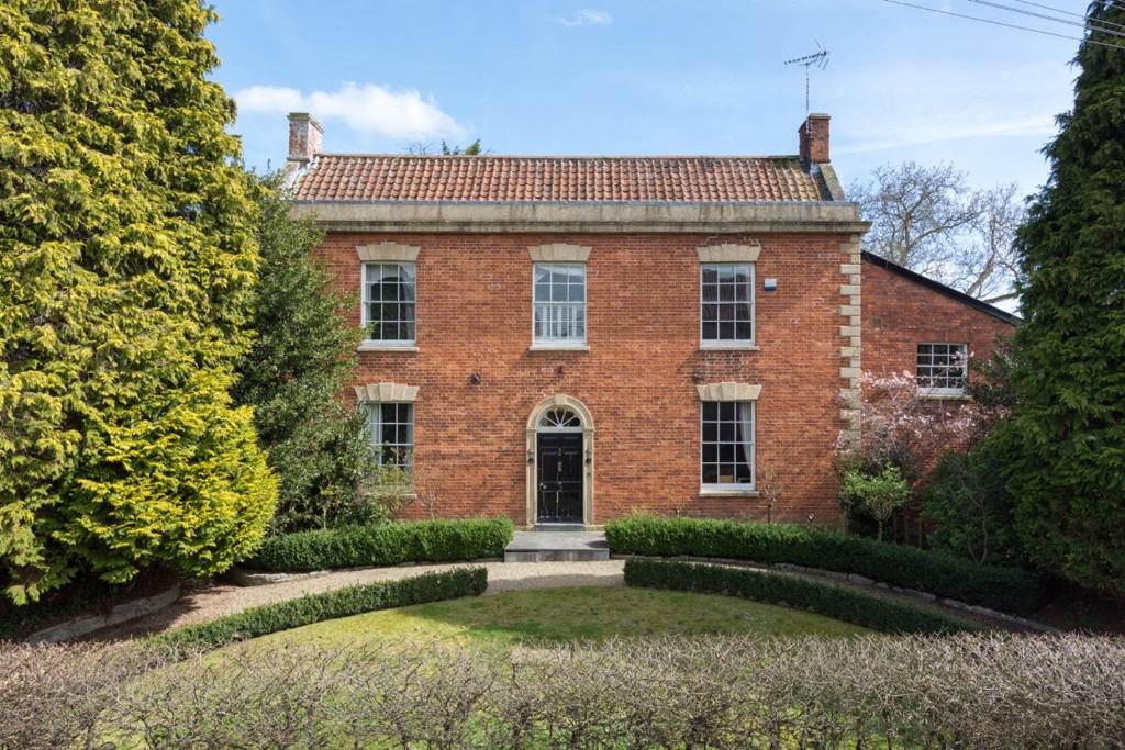 una vieja casa de ladrillo con un jardín delante de ella en Abbots Leigh B&B en Glastonbury