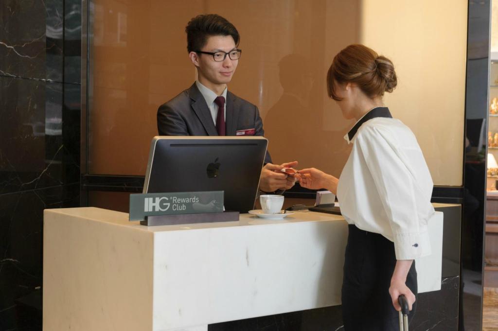 a man and a woman standing at a desk with a laptop at Crowne Plaza Hong Kong Causeway Bay, an IHG Hotel in Hong Kong