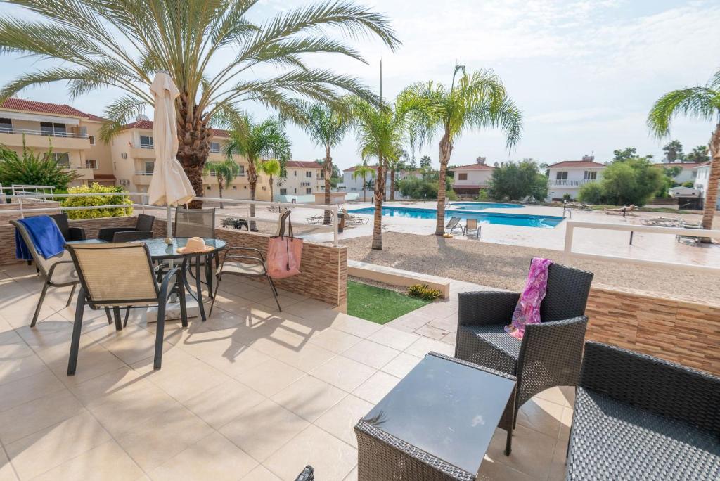 a patio with a table and chairs and a pool at Narcissos 'Nissi Beach' apartment C3 in Ayia Napa