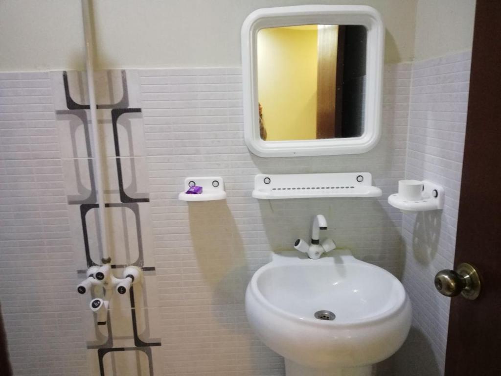 La salle de bains est pourvue de toilettes blanches et d'un miroir. dans l'établissement Seaview Lodge Guest House, à Karachi