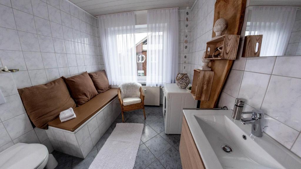 a bathroom with a couch and a toilet and a sink at Willma Apartmenthaus in Beelen