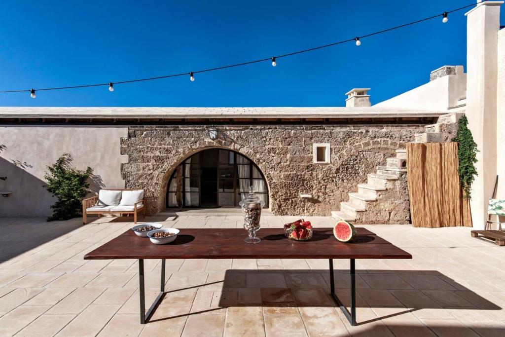 un patio con una mesa y una pared de piedra en Casina Solatia en Nardò