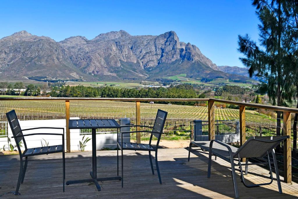 a table and chairs with mountains in the background at Topiary Wine Estate & Cottages in Franschhoek