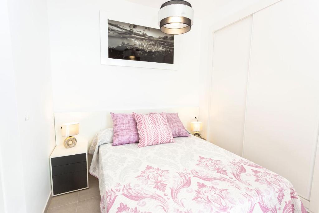 a white bedroom with a bed with pink and purple pillows at Calpe Beach in Calpe