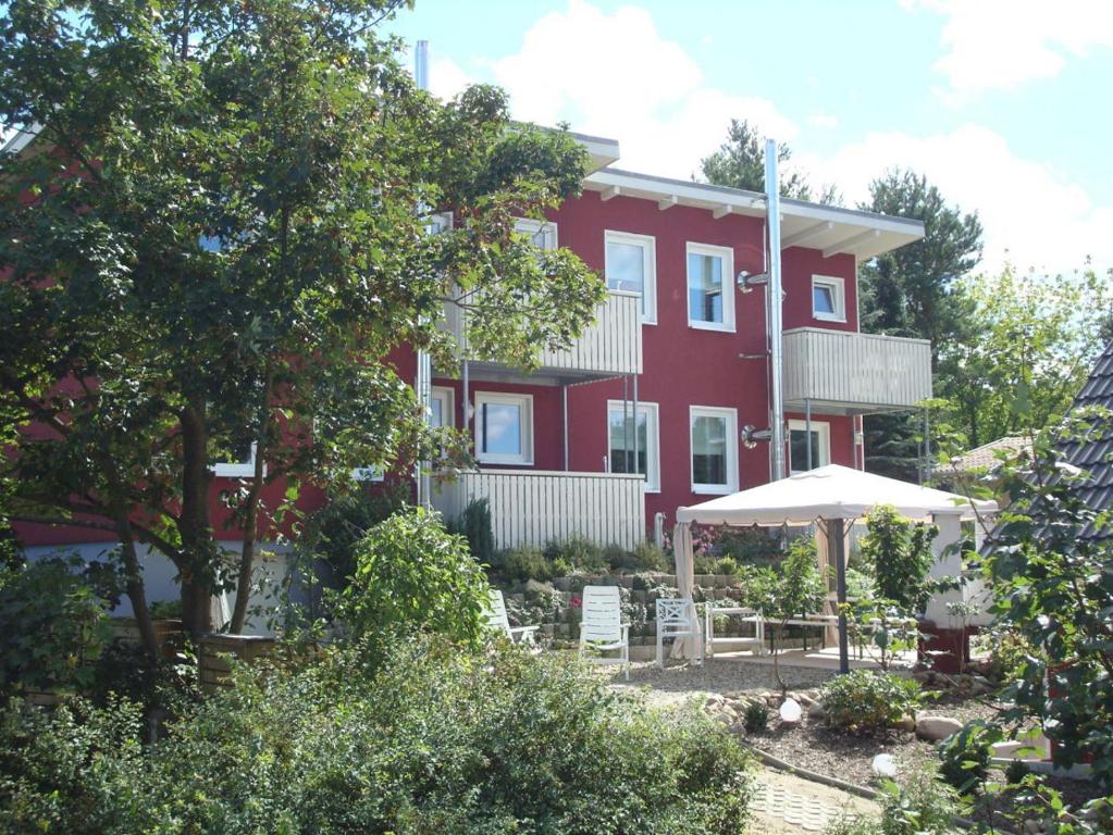 a red house with chairs and an umbrella in front of it at PONTUS Ferienwohnung FeWo2 in Zislow