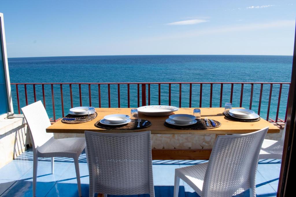 een tafel en stoelen op een balkon met uitzicht op de oceaan bij Beach House Acquamarina in Letojanni