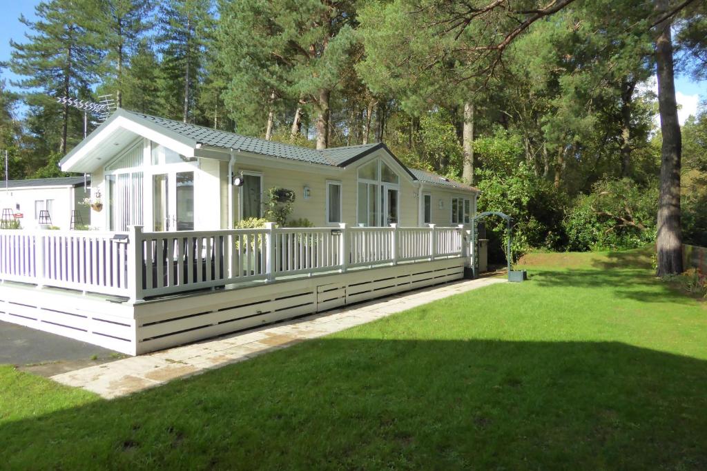 a small white house with a porch and a yard at Violet 28 Oakdene Forest Park in Ferndown