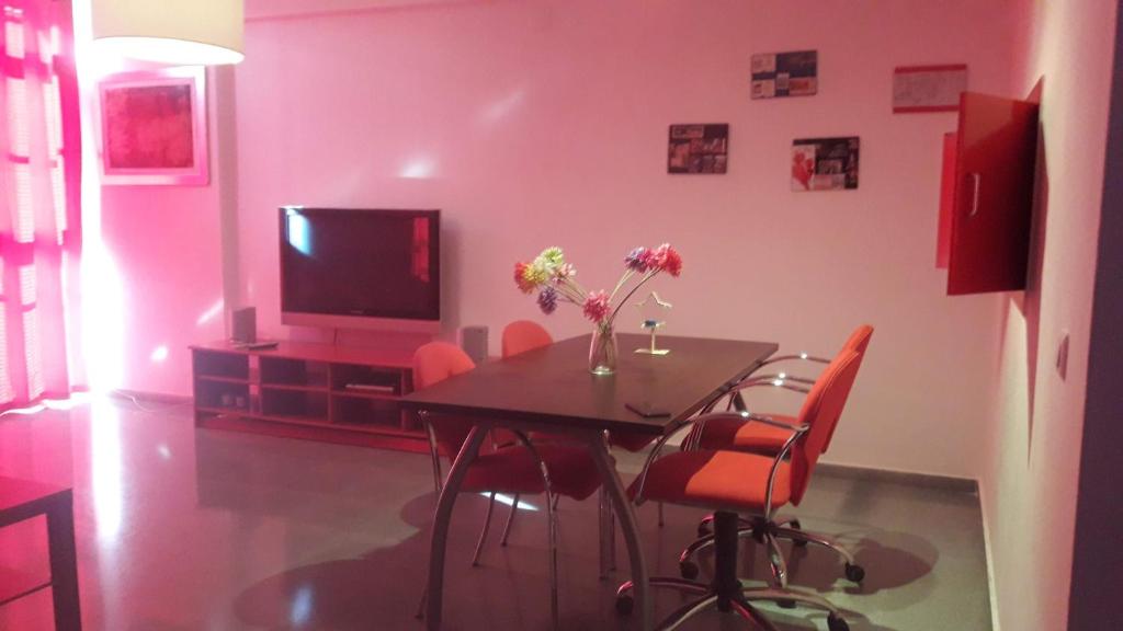 uma sala de jantar com uma mesa com cadeiras e uma televisão em Espacioso Duplex em Sevilha