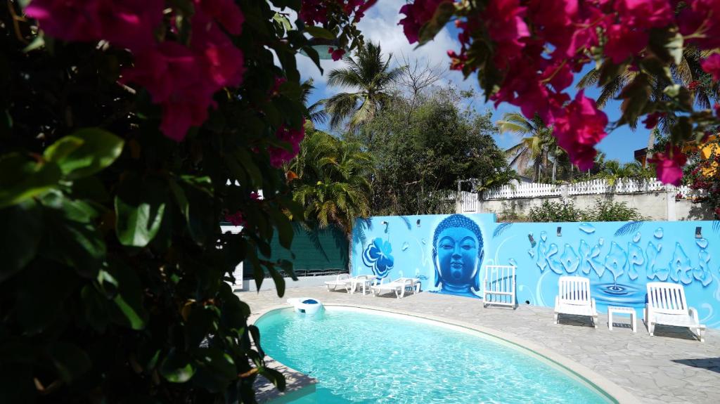 een zwembad met stoelen en een muur met een gezicht erop geschilderd bij Surf camp kokoplaj, A 150m de la Plage et du Spot de Surf in Sainte-Anne