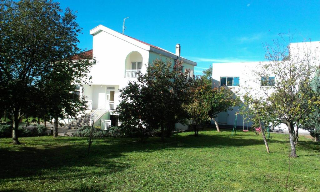 a white building with trees in front of it at Guesthouse Vionica in Međugorje