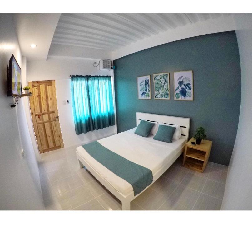a bedroom with a bed and a blue wall at The BIGGIES Inn in Oslob