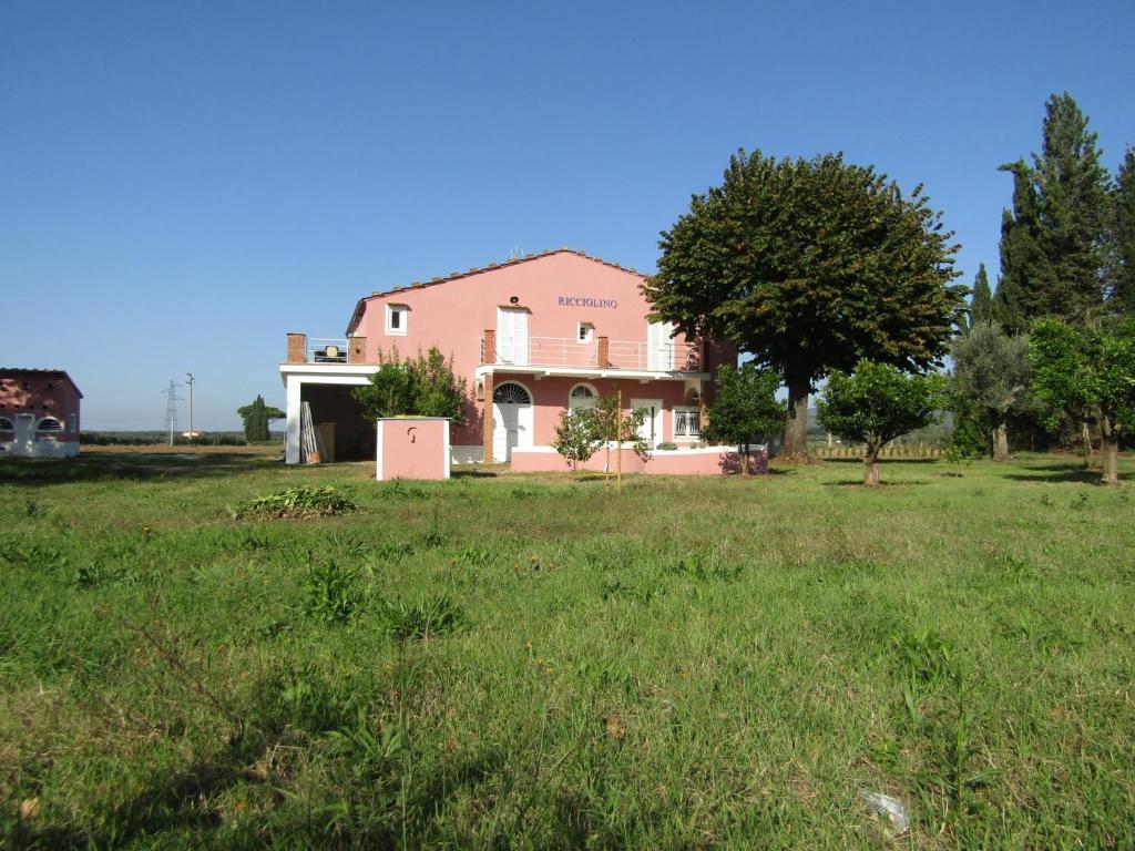 een roze huis in het midden van een veld bij Podere Ricciolino in Castagneto Carducci