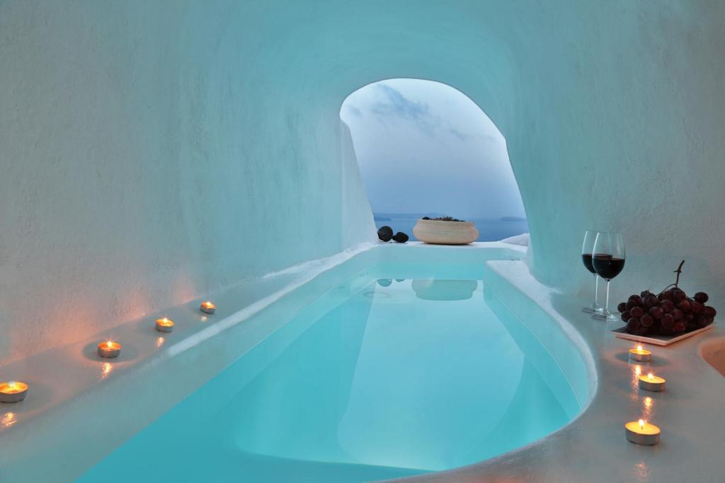 a white bathroom with a tub with a glass of wine at Lava Caves in Oia
