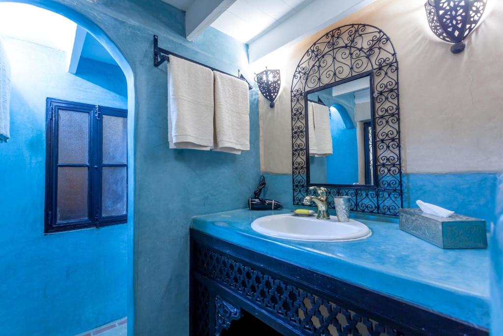 une salle de bain bleue avec un lavabo et un miroir dans l'établissement Riad Hart Essoura, à Marrakech