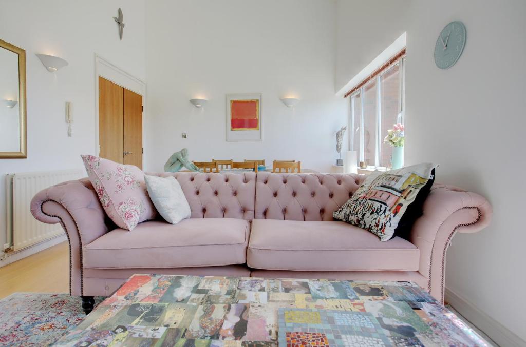 a pink couch in a living room with a table at Beautiful duplex penthouse - roof garden, views, parking in Newcastle upon Tyne