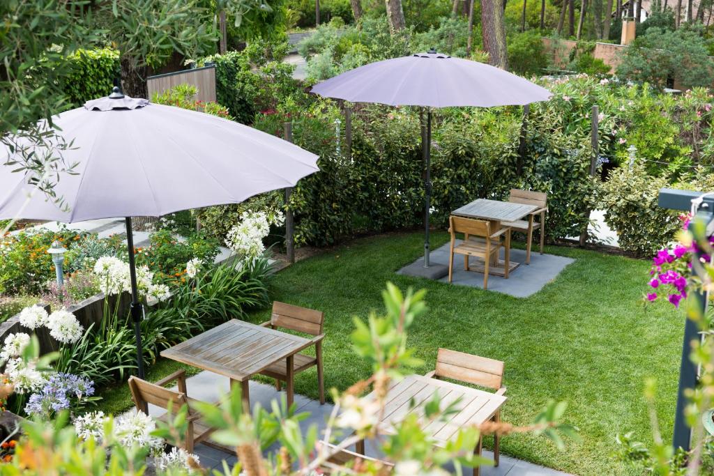 two tables and chairs with umbrellas in a garden at Ferret Vigne - Villa Chambres d&#39;Hôtes in Cap-Ferret