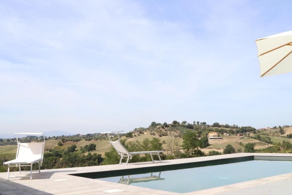 a swimming pool with two lawn chairs and a table and chairs at Agriturismo Casale Contessa in Montebuono