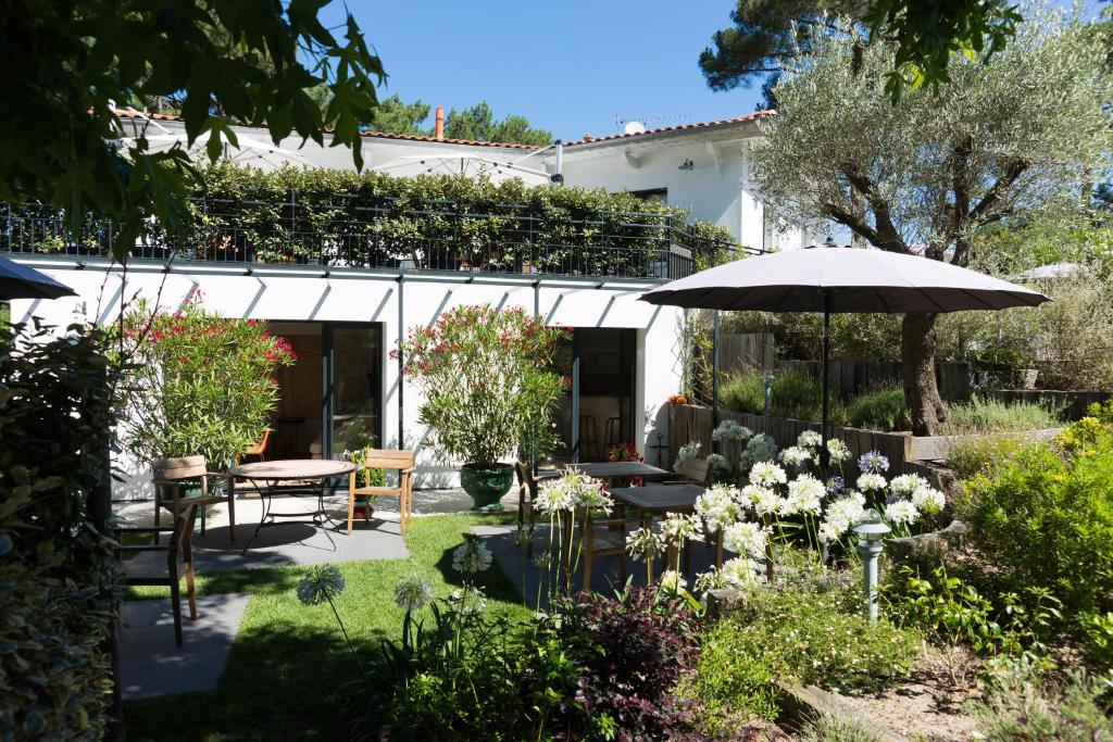 a garden with a table and an umbrella at Ferret Vigne - Villa Chambres d'Hôtes in Cap-Ferret