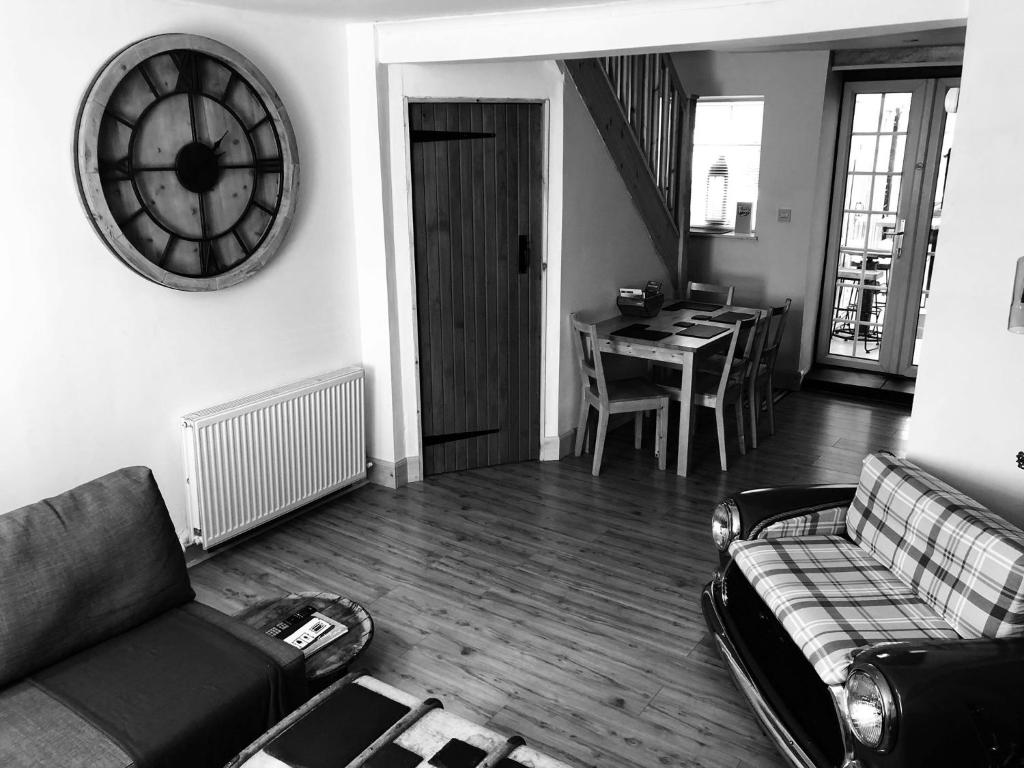 a living room with a couch and a clock on the wall at Fisher Holiday Cottage Ayrshire in Girvan