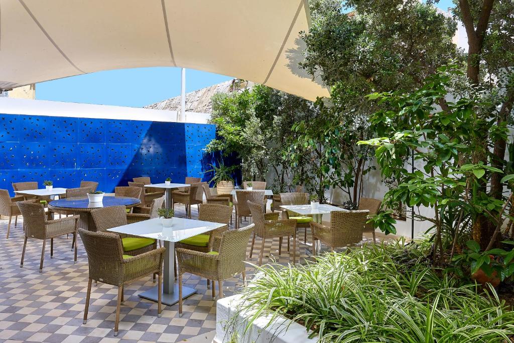 an outdoor patio with tables and chairs and trees at Atrion Hotel in Heraklio