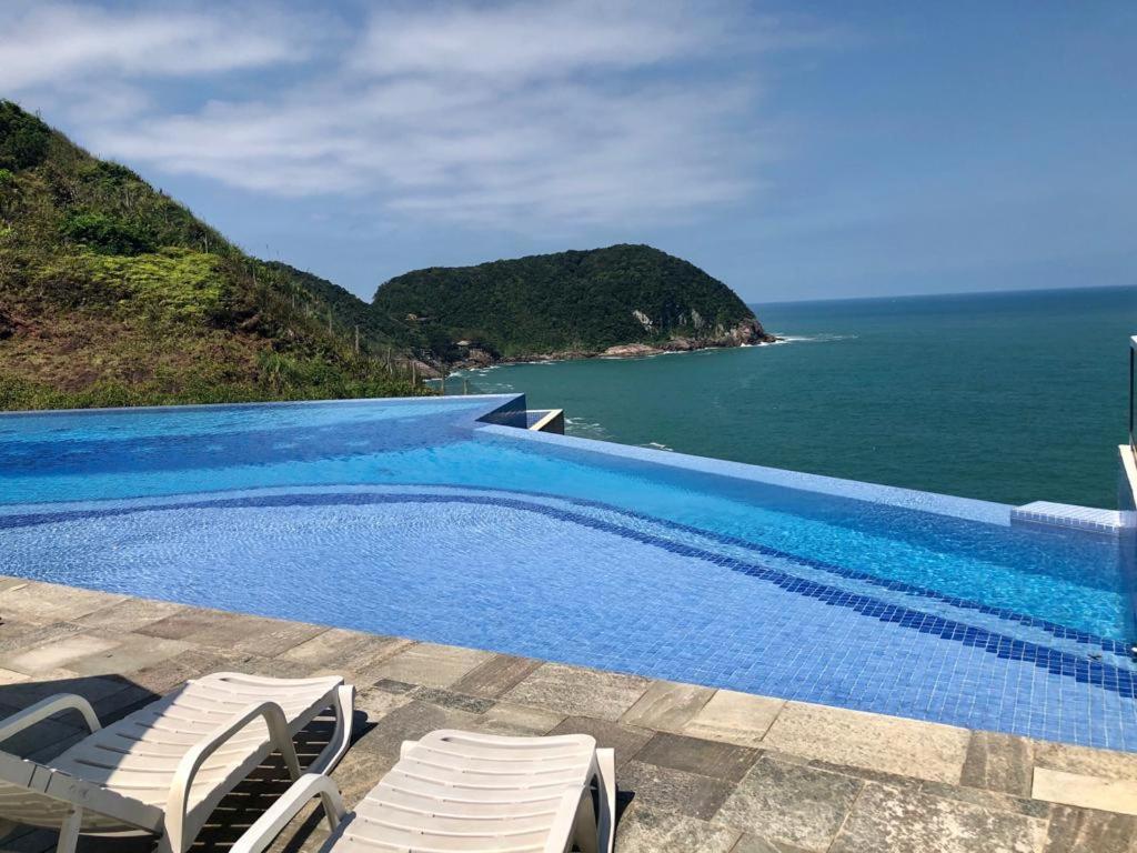 a swimming pool with a view of the ocean at Apartamento Familiar Guaruja in Guarujá