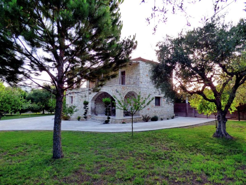 uma casa de pedra com duas árvores em frente em Rouveli Villa with private garden and barbeque em Tragaki