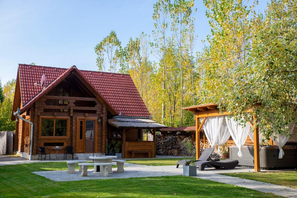 uma cabana de madeira com uma mesa de piquenique e um pavilhão em Körösparti wellness faház em Gyomaendrod