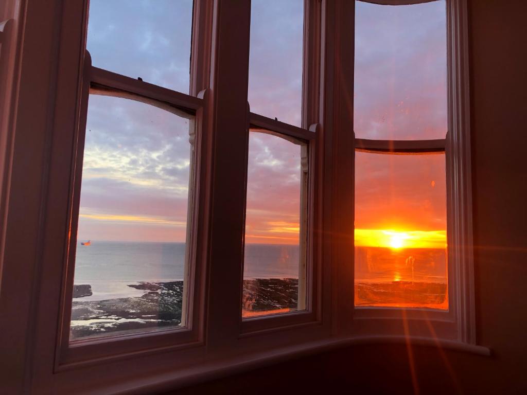 a window with a view of the sunset seen through it at The Lido View Terrace in Margate