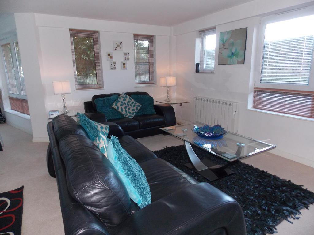 a living room with a leather couch and a glass table at Waterside Apartment in Lancaster