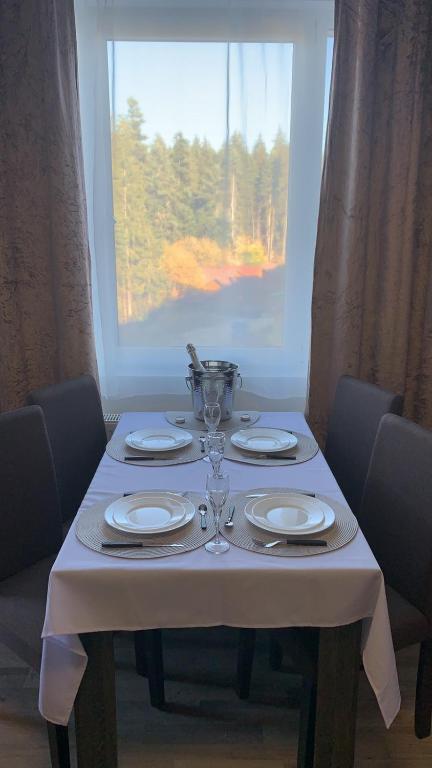 a table with plates and glasses on it with a window at ComfortApartment IGLIKA 2 in Borovets